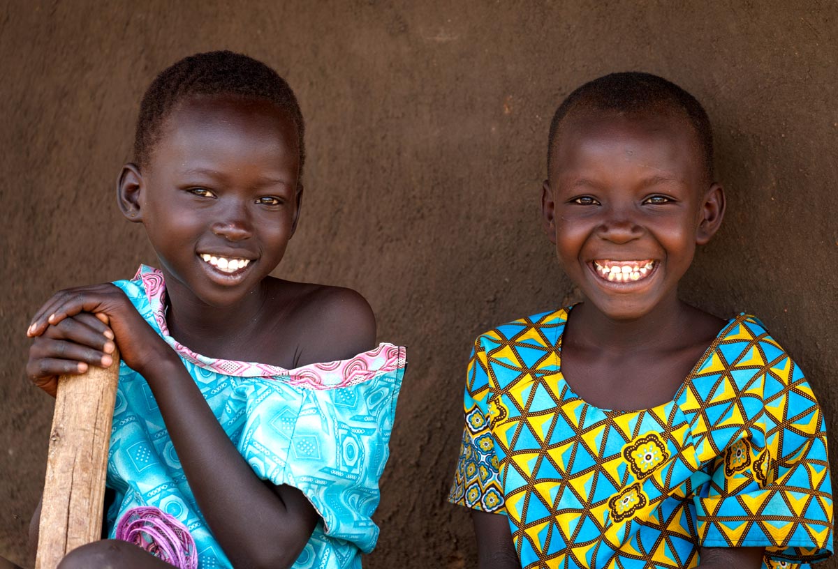 Two smiling Ugandan young girls wearing bright colorful clothing